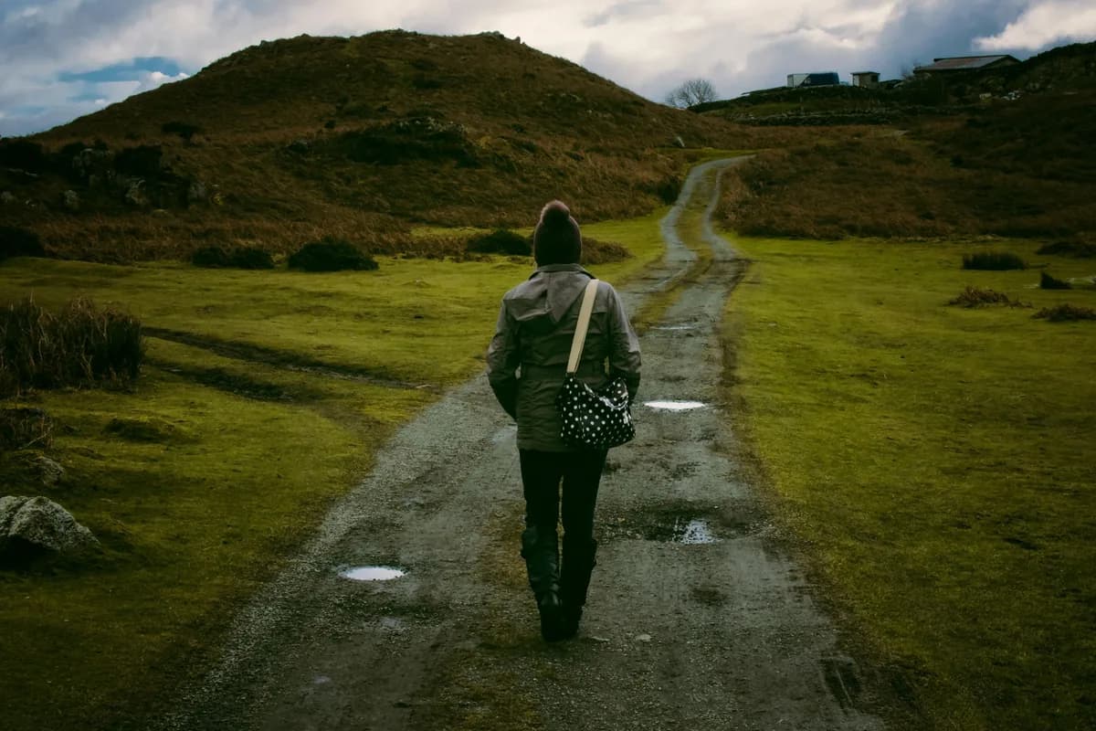 A person walking alone along a path through open countryside