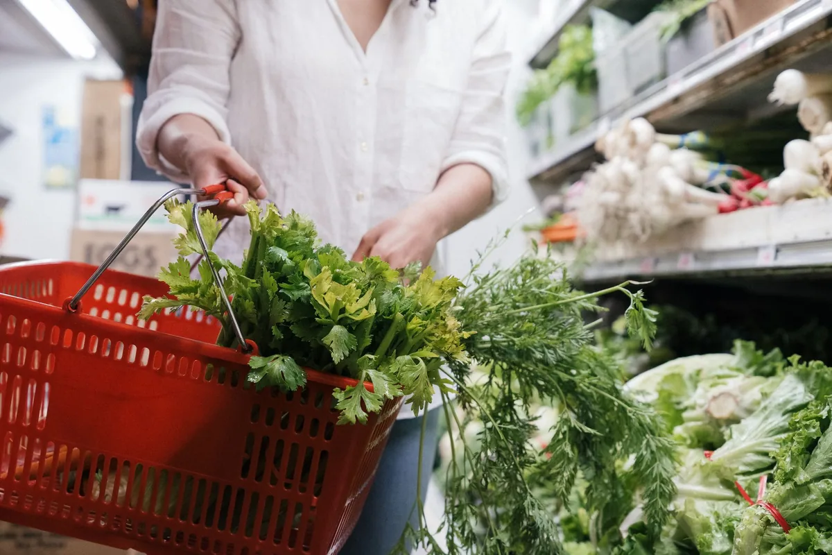 Hands holding a basket of fresh green vegetables at a market