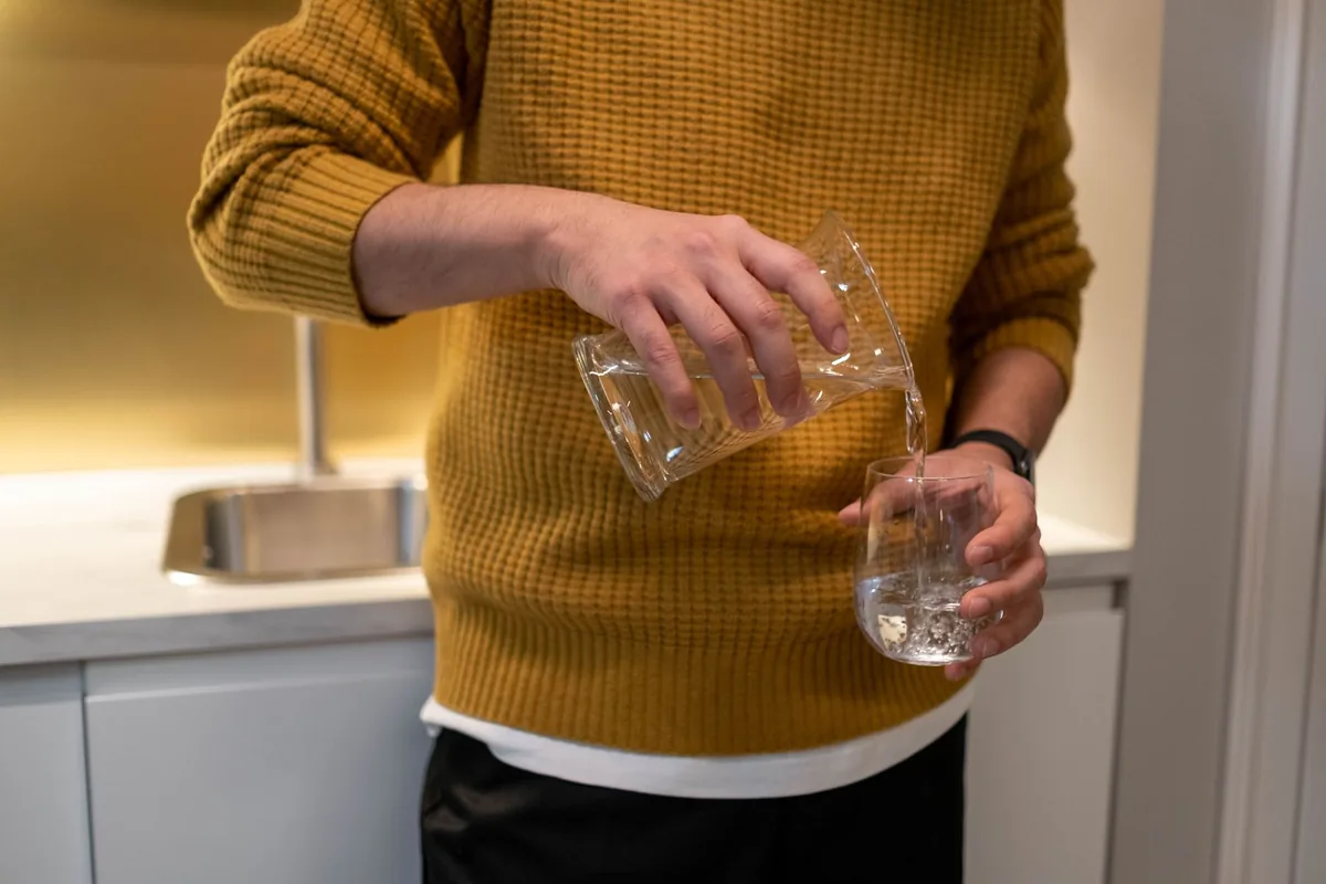 A person pouring a glass of water in a kitchen