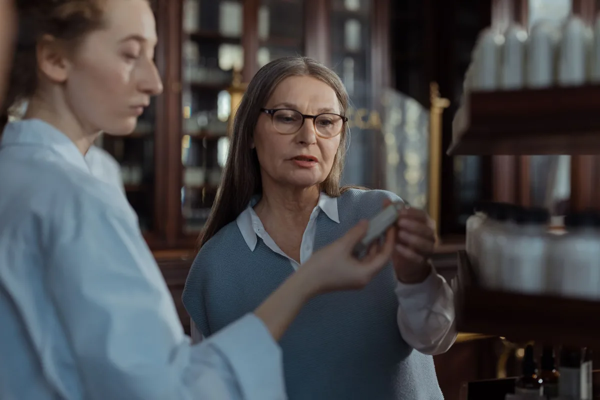 A pharmacist advising a customer beside pharmacy shelves